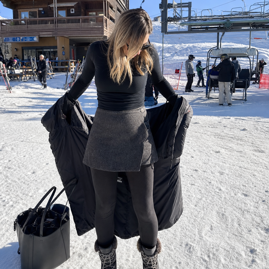 Woman switching from ski parka to a tweed wrap mini skirt at the lift base