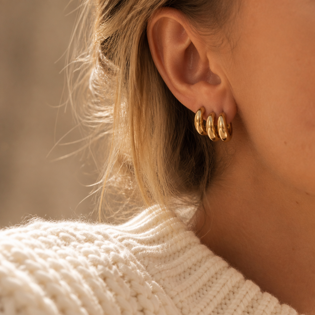 Close-up of stacked gold huggie hoop earrings